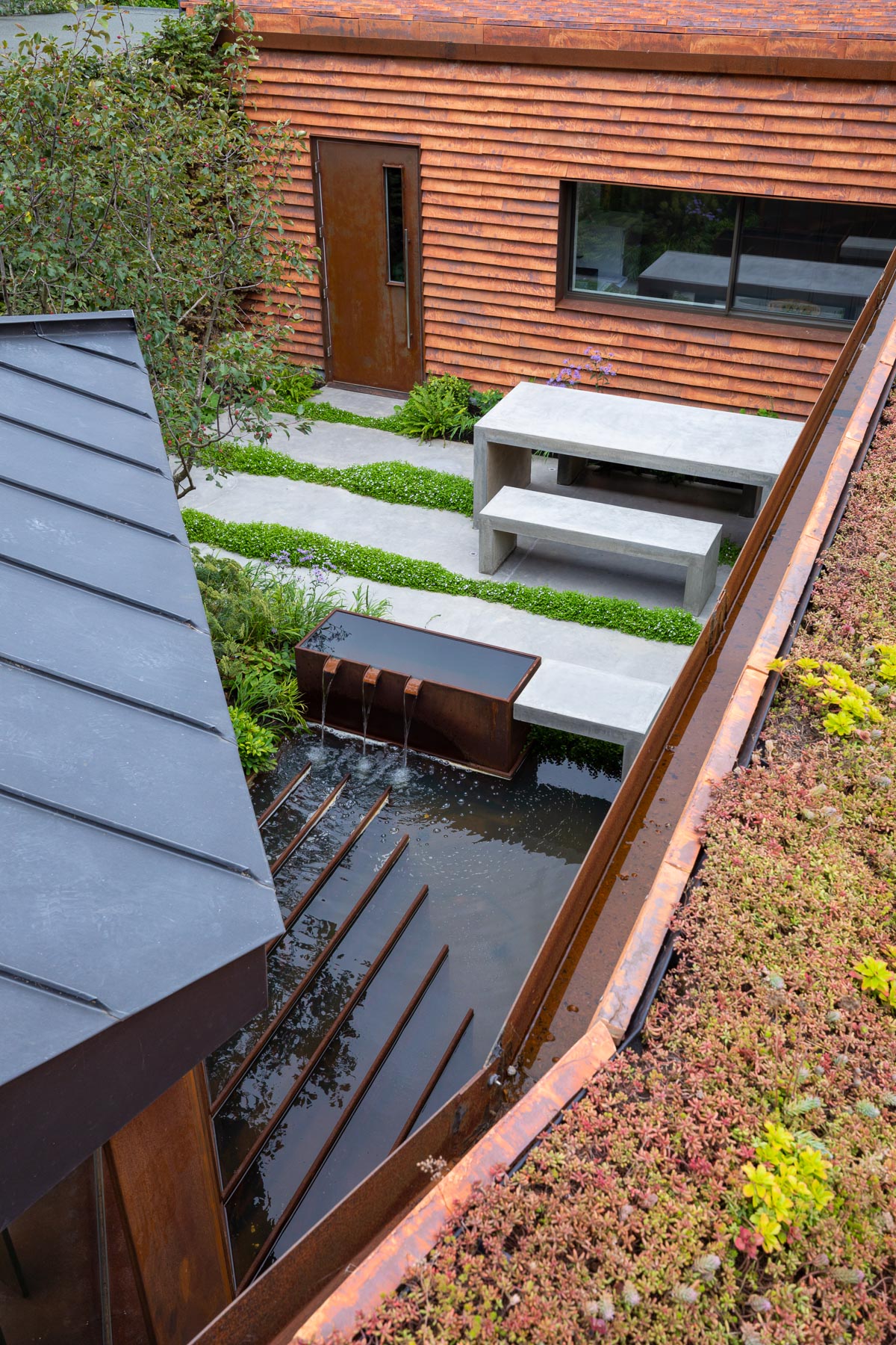 Colm Joseph modern design Cambridge Petersen bricks architecture corten steel water feature concrete table and benches naturalistic planting view from above